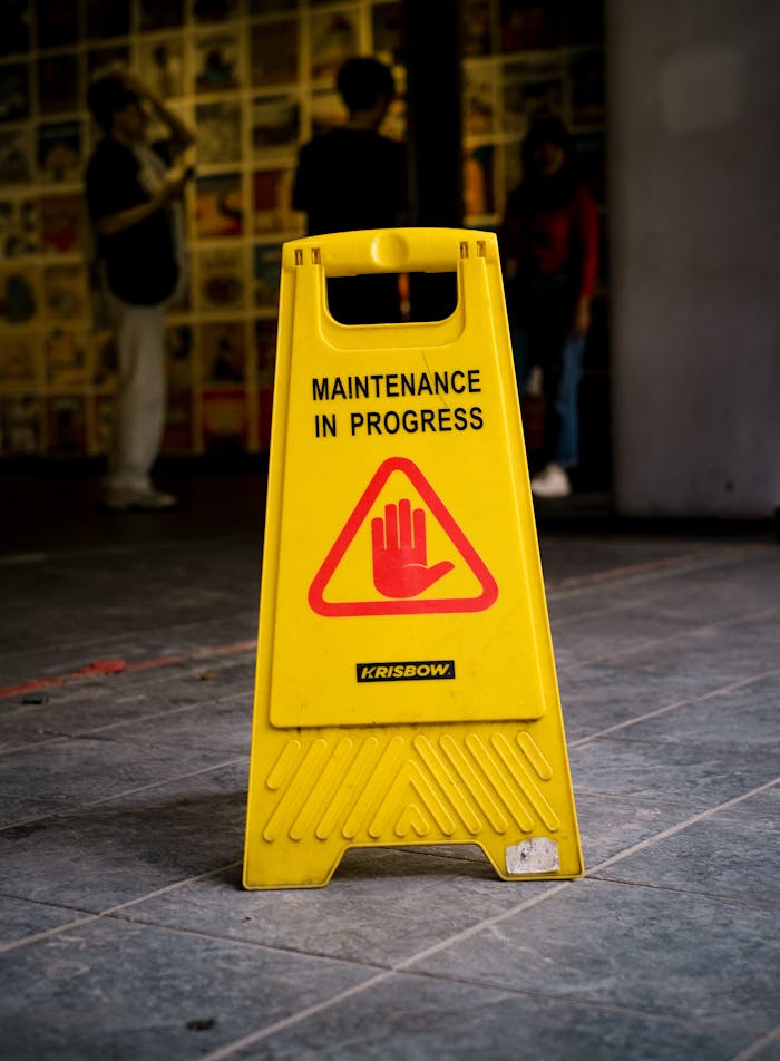 who-we-are Bright yellow 'Maintenance in Progress' sign on tiled pavement in Jakarta, Indonesia.